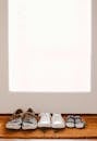 A collection of family shoes, including baby booties, on a welcoming mat by the door.